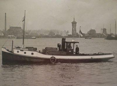 Kazoo in 1931 met aan het roer eigenaar en kaptein L. Dooms op de Oude Maas ter hoogte van  de watertoren van Zwijndrecht met de houtzaagmolen aan het Balkengat.