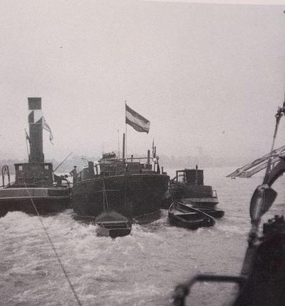 Een Vulcaan boot geeft voorspan op de resten van de opgeblazen Rijnbrug bij Urmitz met langszij de Neptunus. 